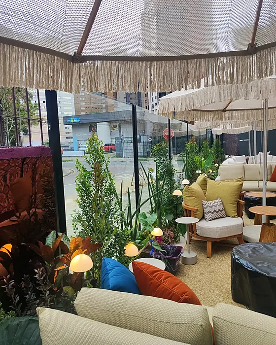 Varanda com sofás e ombrelones, ambiente da Casa Cor 2026